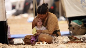 A refugee woman from the minority Yazidi sect, who fled the violence in the Iraqi town of Sinjar, sits with a child inside a tent at Nowruz refugee camp in Qamishli, northeastern Syria August 17, 2014. Proclaiming a caliphate straddling parts of Iraq and Syria, Islamic State militants have swept across northern Iraq, pushing back Kurdish regional forces and driving tens of thousands of Christians and members of the Yazidi religious minority from their homes. Picture taken August 17, 2014. REUTERS/Rodi Said   (SYRIA - Tags: POLITICS CIVIL UNREST CONFLICT TPX IMAGES OF THE DAY)